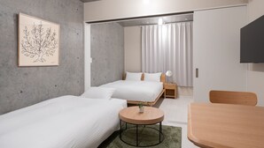 A modern hotel room with two single beds, a round wooden table, a small potted plant, a framed artwork on the wall, and a TV mounted on the wall. - MINI HOUSE Tokyo South (Tokyo)