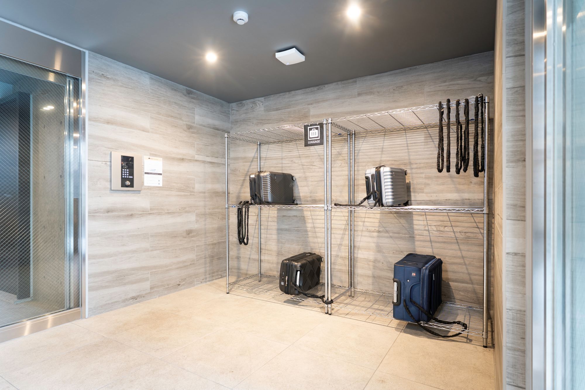 A luggage storage area with metal shelves, a security camera, and a sign indicating 'LUGGAGE'.