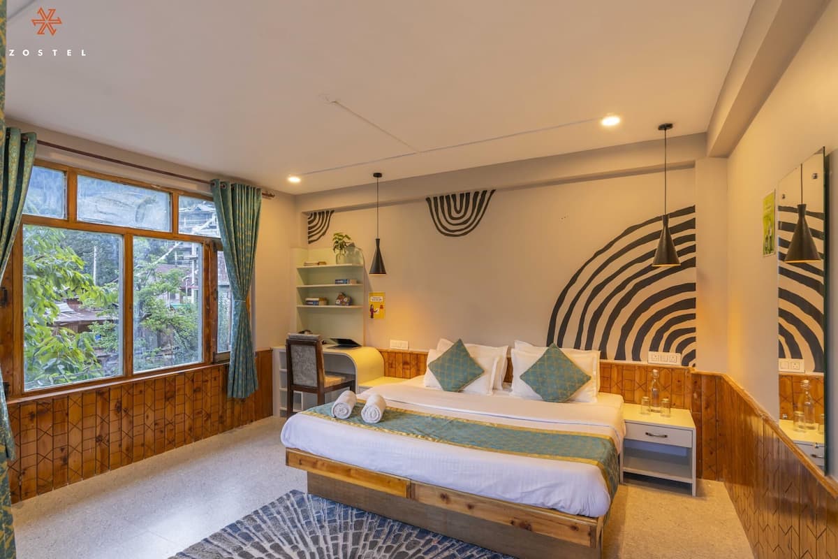 A bedroom with a bed, bedside tables, a desk, and a window with curtains.