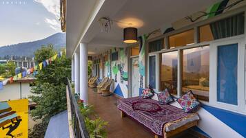 A balcony with wicker chairs, a patterned bed, and a view of mountains.