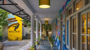 Un pasillo cubierto con un mural, plantas en macetas y una pared de piedra.