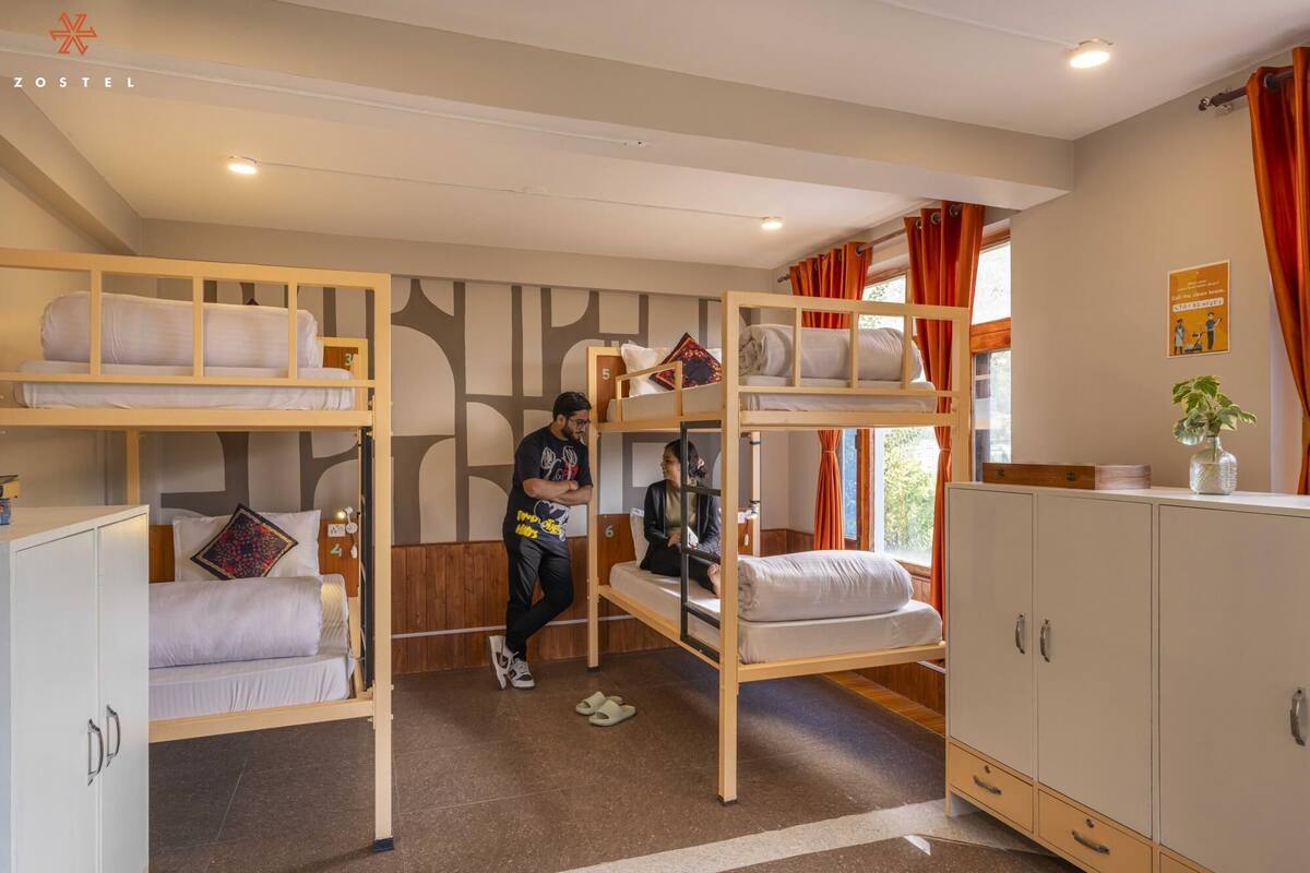 A dormitory room with bunk beds, a wardrobe, and a small desk.
