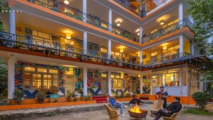 Un edificio de varios pisos con balcones, mobiliario exterior y una fogata.
