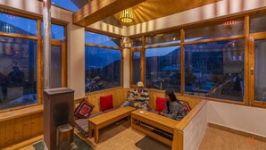 Una habitación acogedora con muebles de madera, ventanas amplias y vistas a las montañas.