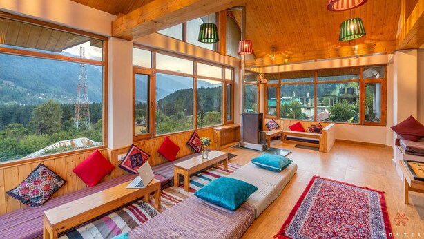 Una habitación acogedora con ventanas amplias, muebles de madera y cojines de colores.
