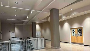 A spacious lobby with a high ceiling, a central column, and a staircase with metal railings. - Luxury, centrally located loft Downtown w/skybridge access to Convention Center (Indianapolis)