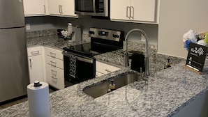 A modern kitchen with white cabinets, a granite countertop, stainless steel appliances, and a built-in oven. - Luxury, centrally located loft Downtown w/skybridge access to Convention Center (Indianapolis)