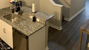 A kitchen with a granite countertop, stainless steel sink, and a wooden stool. - Luxury, centrally located loft Downtown w/skybridge access to Convention Center (Indianapolis)