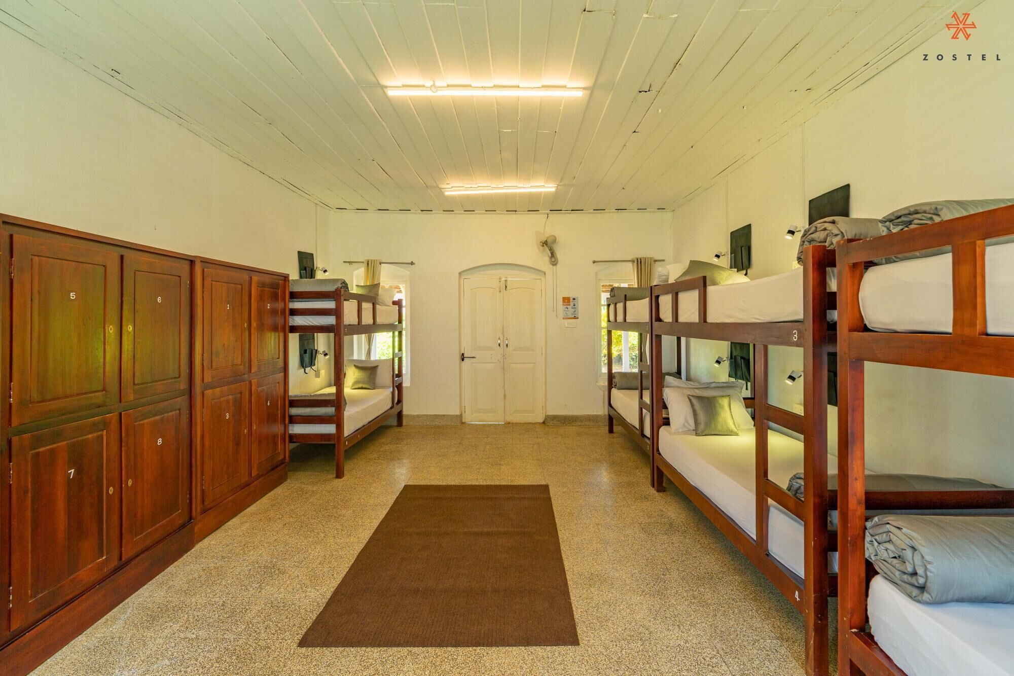 Una habitación tipo dormitorio con literas, armarios de madera y una puerta.