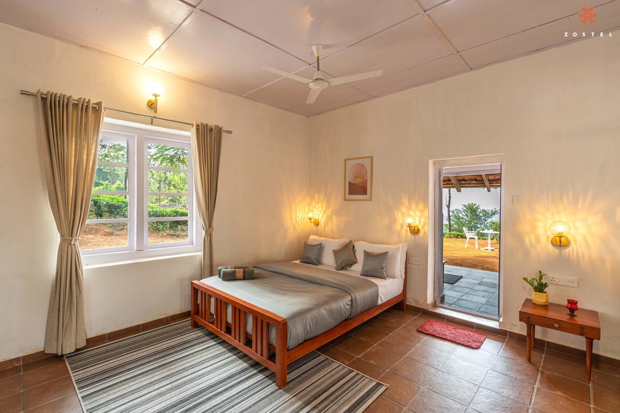 Un dormitorio con cama, cortinas, ventana, ventilador de techo y puerta que da al exterior.