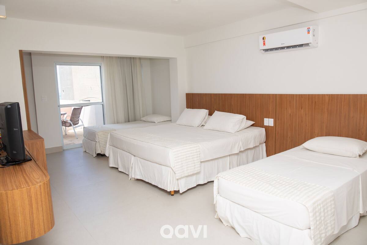 A hotel room with two beds, a wooden desk, and an air conditioning unit.