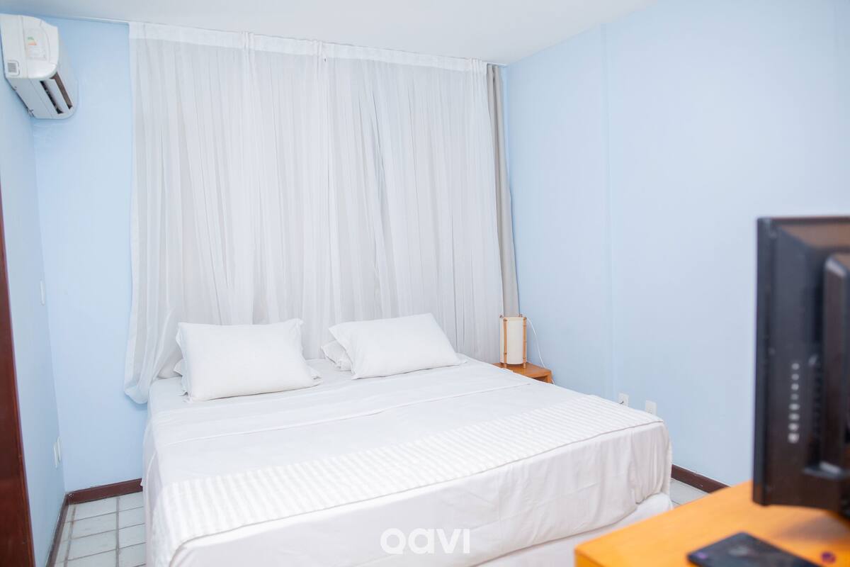 A hotel room with a bed, a TV, and a bedside table.