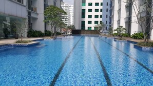 A swimming pool with clear blue water, surrounded by modern buildings and greenery. - M Suites Jalan Ampang (Kuala Lumpur)
