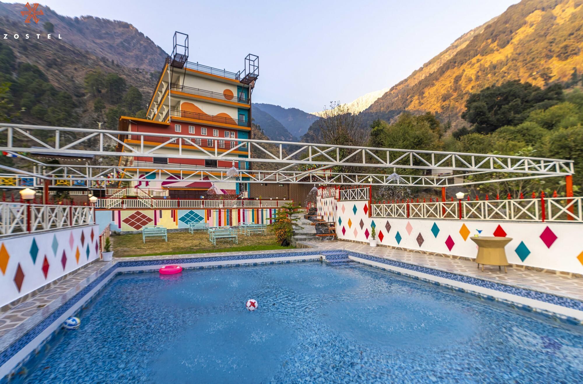 Une piscine offrant une vue sur un bâtiment aux couleurs vives et sur des montagnes en arrière-plan.
