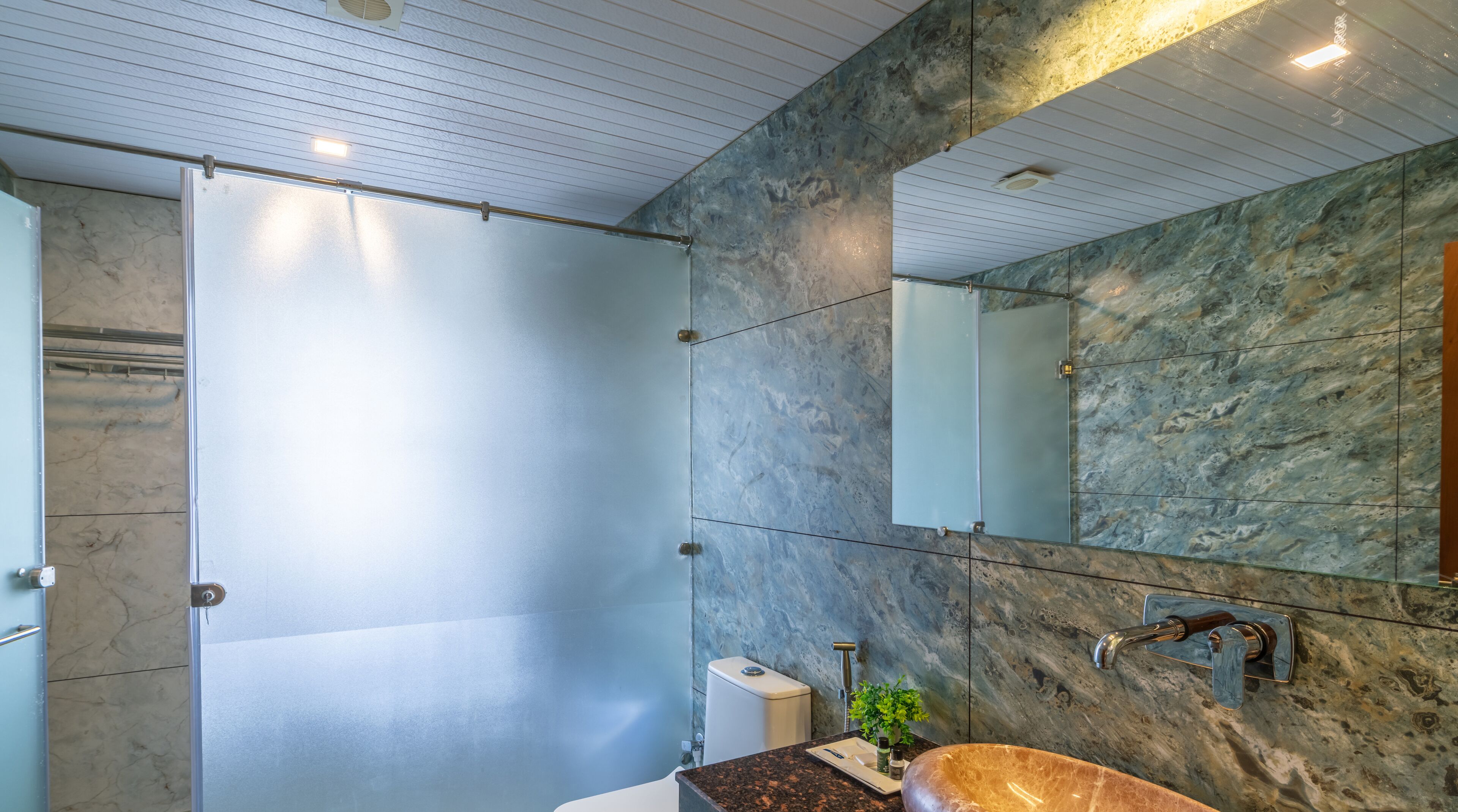 A modern bathroom with a glass shower enclosure, a marble backsplash, and a sink with a wooden countertop.