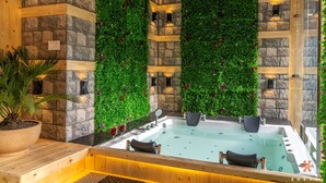A spa area with a stone wall, green wall, and a hot tub. - Zostel Plus Kareri (Dharamshala)
