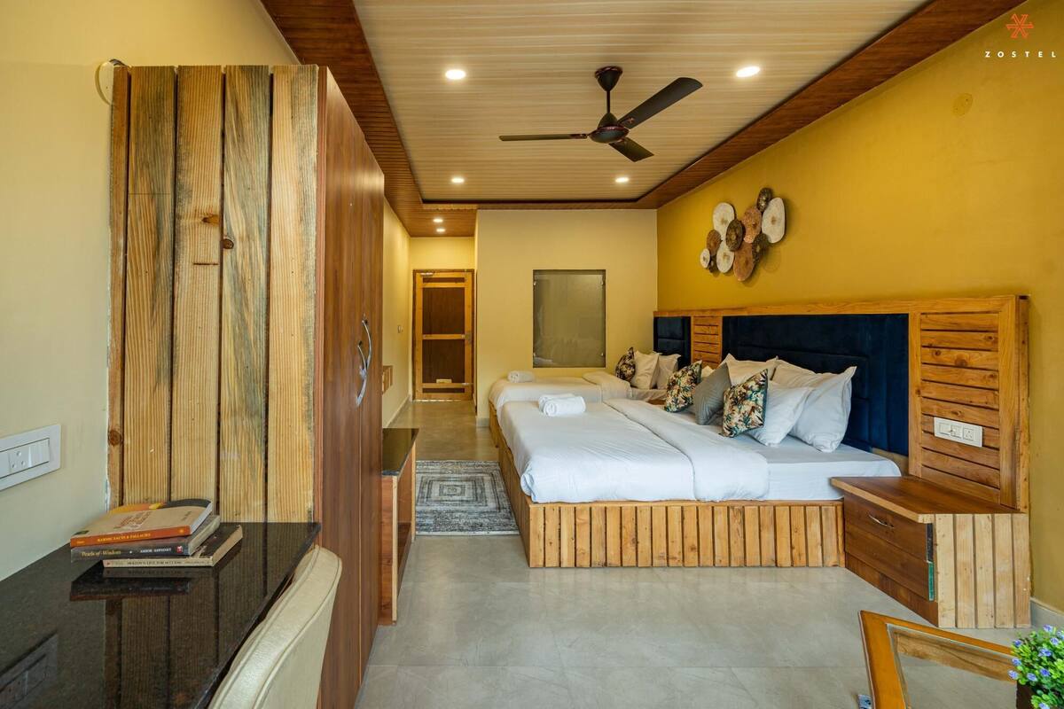 A bedroom with a wooden headboard, two beds, a ceiling fan, and a small bedside table.