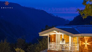 A wooden cabin with a balcony, surrounded by mountains. - Zostel Plus Kareri (Dharamshala)