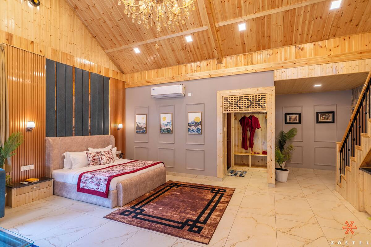 A spacious room with a large bed, a wooden ceiling, and a staircase leading to another level.