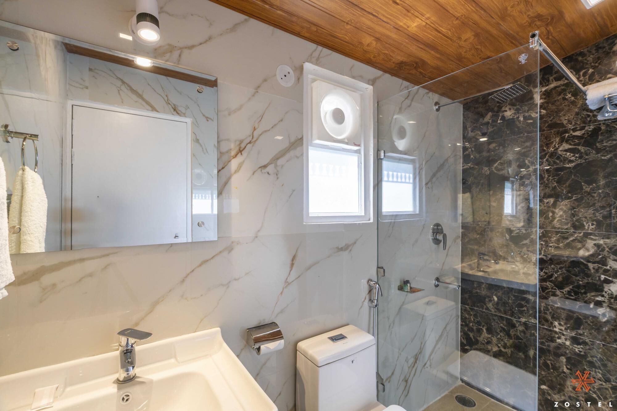 Une salle de bain moderne avec un meuble-lavabo en marbre, une cabine de douche en verre et un plafond en bois.