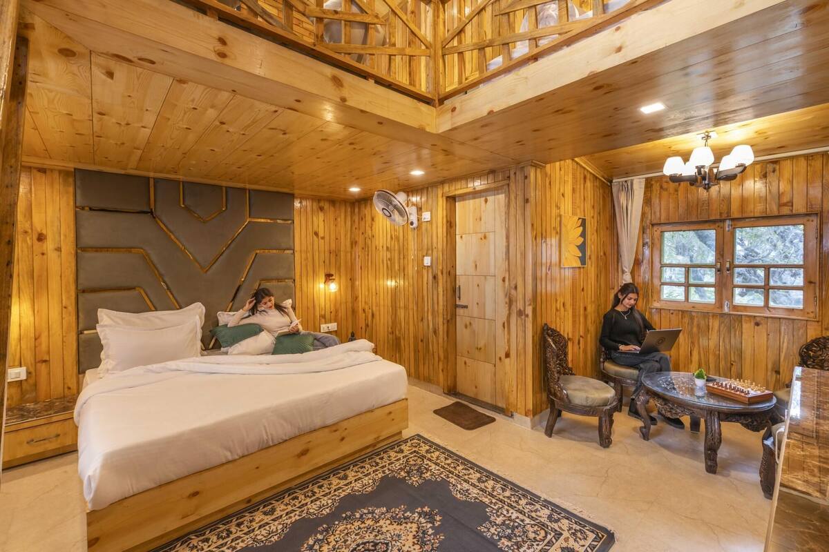 A wooden cabin room with a bed, a desk, and a chair.