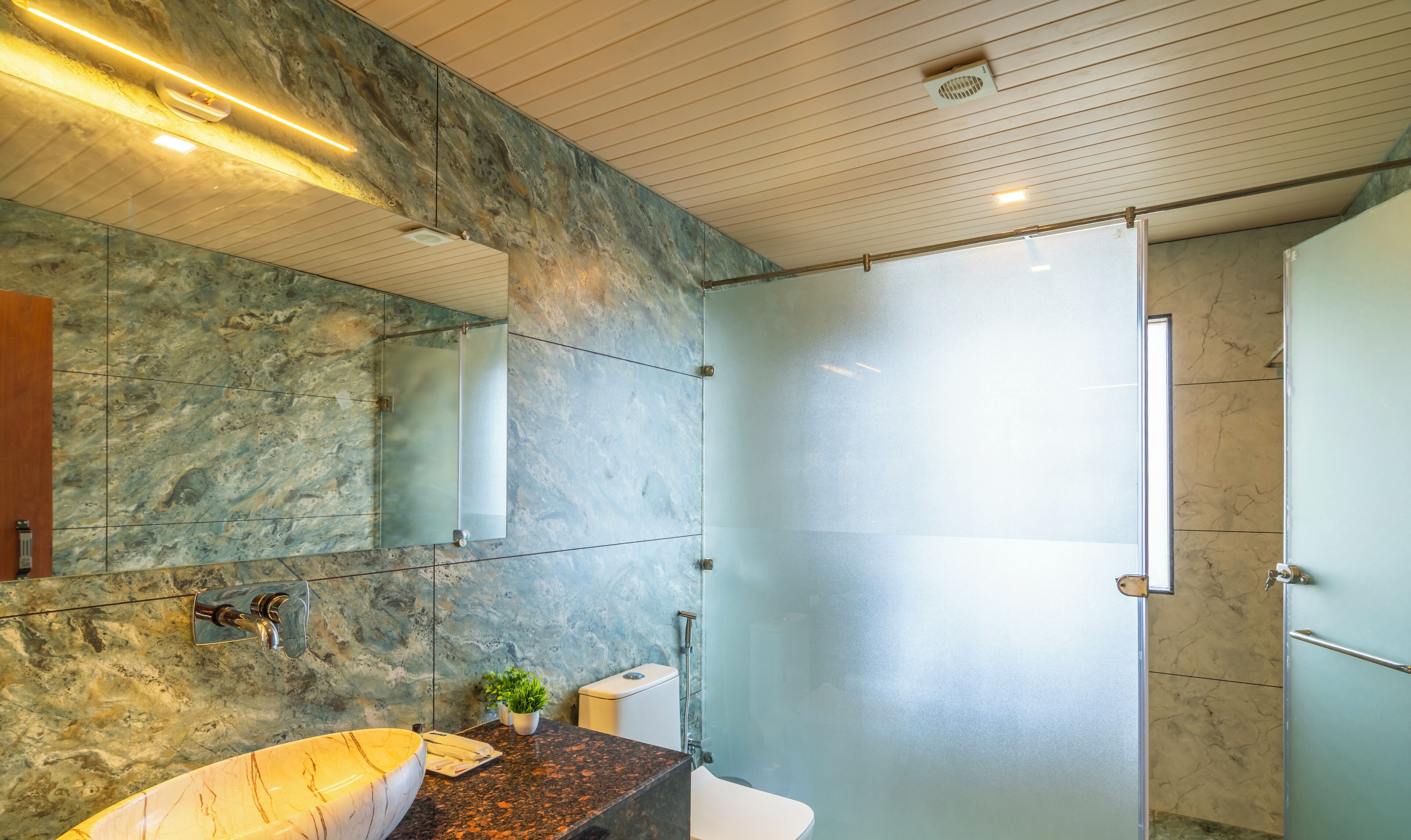 A modern bathroom with a marble sink, a glass shower enclosure, and a large mirror.
