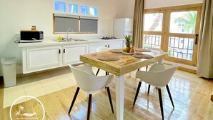 A modern kitchen with white cabinets, a wooden ceiling, and a dining area with a wooden table and white chairs. - C-402 Loft apt in Punta Cana, los Corales Beach/pool (Punta Cana)