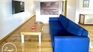 A modern living room with a blue sofa, wooden coffee table, and a flat-screen TV mounted on the wall. - C-402 Loft apt in Punta Cana, los Corales Beach/pool (Punta Cana)