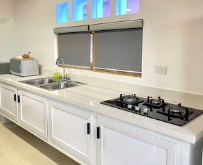 A modern kitchen with a white countertop, stainless steel sink, and a gas stove.
