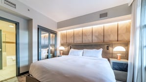 Ein modernes Hotelzimmer mit einem großen Bett, Nachttischlampen und Blick ins Badezimmer.