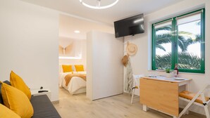 Una habitación moderna y luminosa con una cama, un escritorio y un televisor.