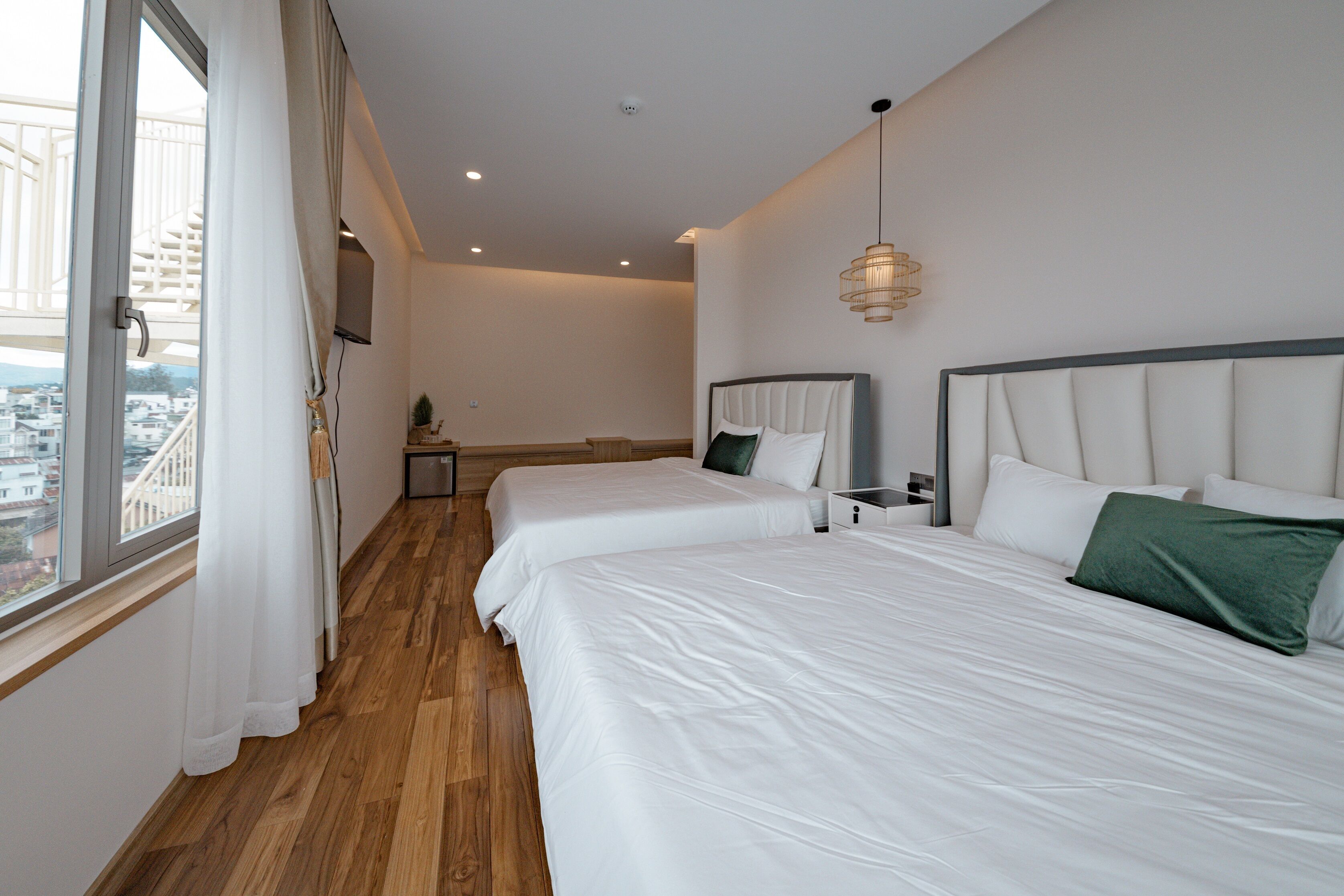 Une chambre d’hôtel avec deux lits, une grande fenêtre et une vue sur la ville.