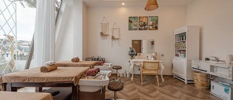 Un salón de spa con camillas de masaje, una recepción y vistas a la ciudad.