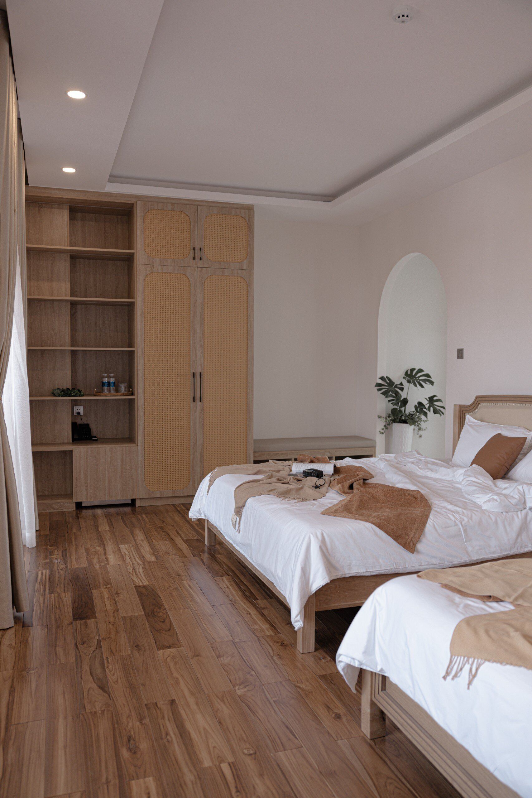 Une chambre avec deux lits, une armoire en bois et une plante sur la table de chevet.