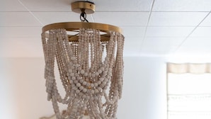 Une chambre à coucher avec un lit, un lustre et une fenêtre avec des rideaux.