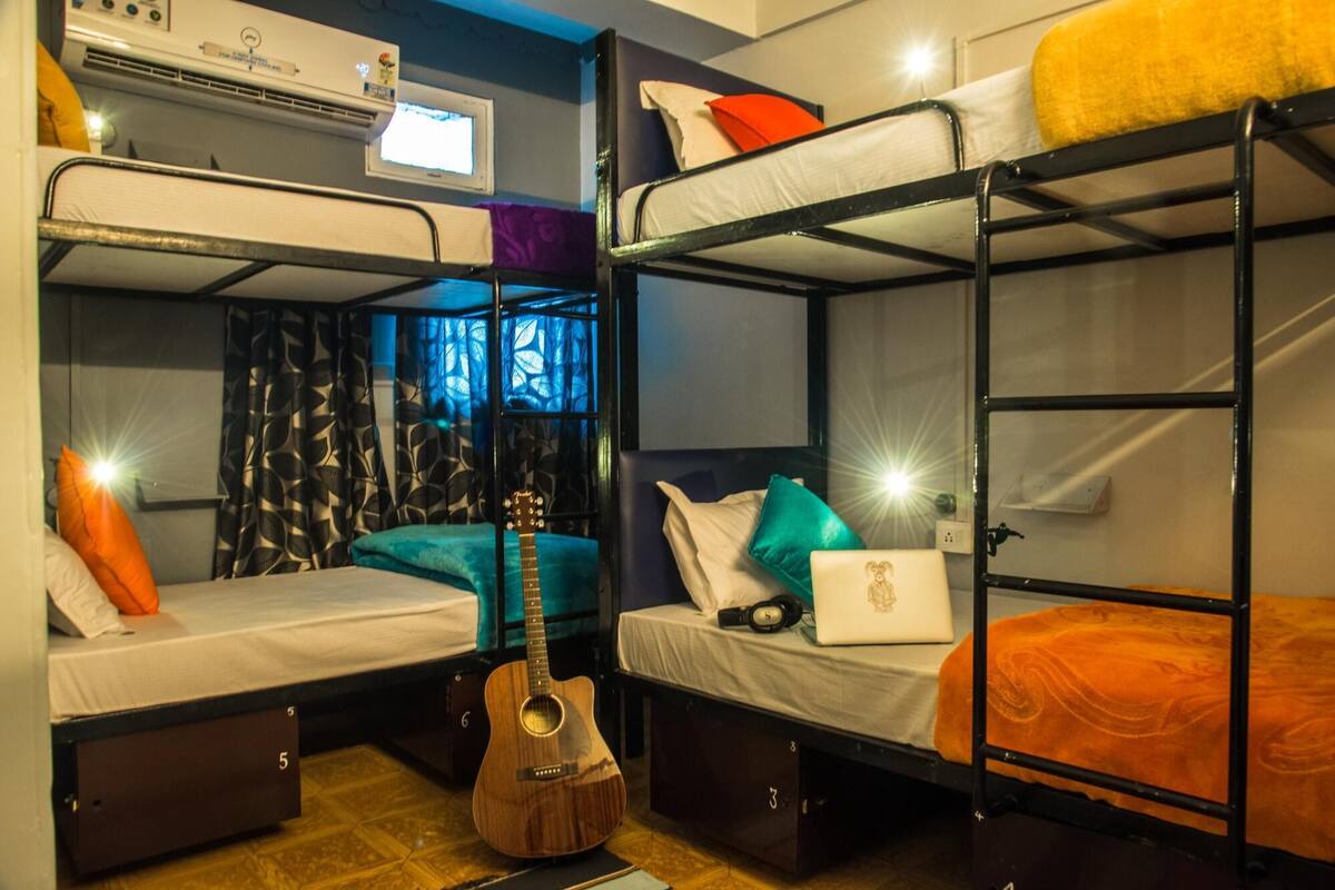 Un dormitorio con literas, una guitarra y una laptop sobre una de las camas.