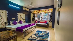 A room with two beds, a small table, a rug, and a window with a view of the street. - Zostel Jodhpur - Clock Tower (Jodhpur)