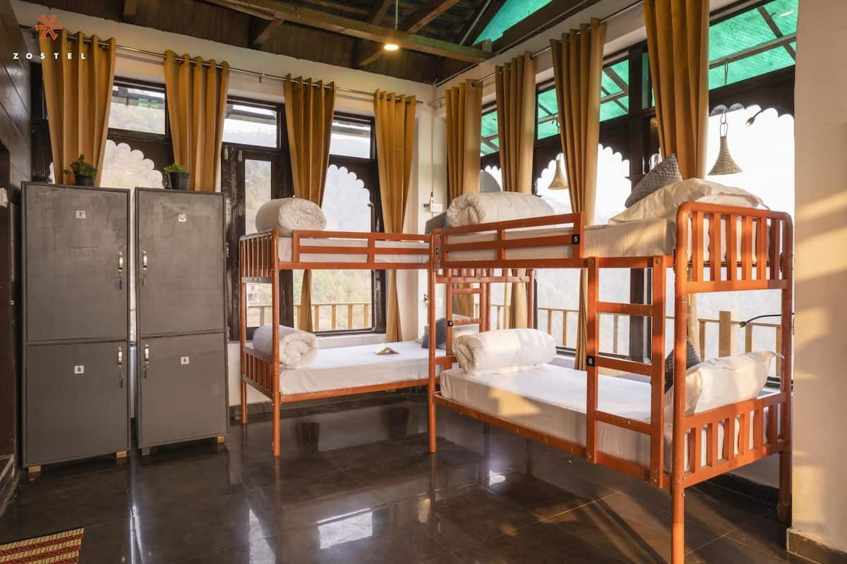 Een slaapzaal met stapelbedden, een kledingkast en een raam met gordijnen.