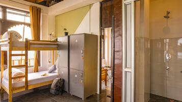 Une chambre de dortoir avec des lits superposés, une armoire et un espace douche.