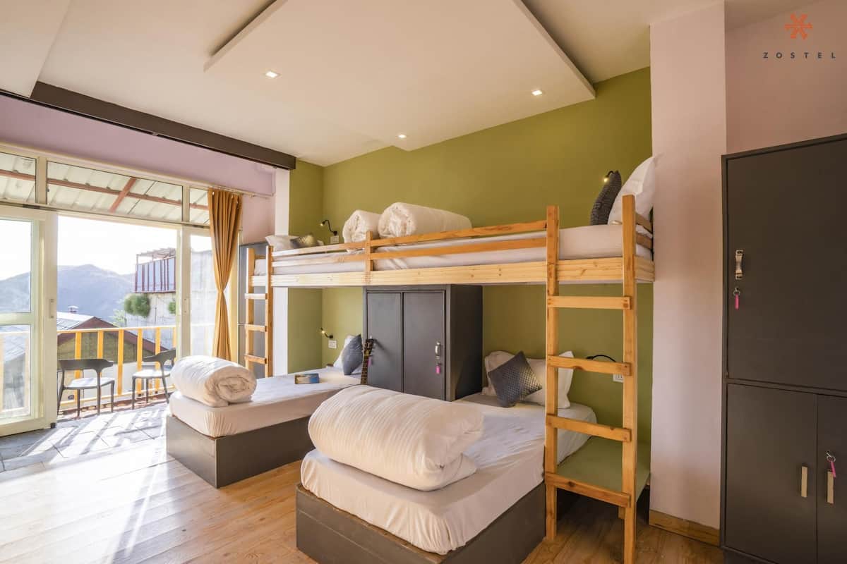 Een slaapkamer met een stapelbed, een garderobe en een balkon.