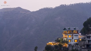 A multi-story building with balconies, situated on a hillside with a mountainous backdrop. - Zostel Banikhet (Dalhousie)