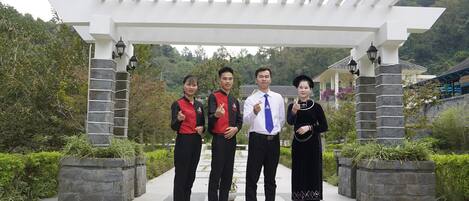 A group of people standing under a pergola with a banner for Saigon-Bang Gioc Resort.