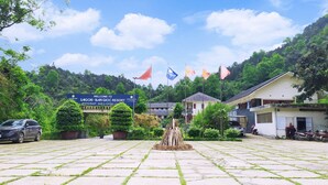 A resort entrance with a paved area, a signboard, flags, and buildings.