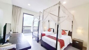 A four-poster canopy bed with white bedding and red accents, a television, and a desk with a chair in a hotel room.