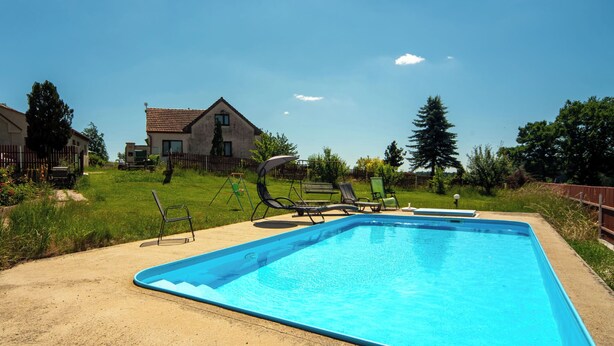 A rectangular swimming pool with a clear blue water surface, surrounded by a concrete deck.
