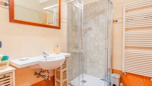 A bathroom with a white sink, a mirror, a shower with patterned tiles, and a towel rack.