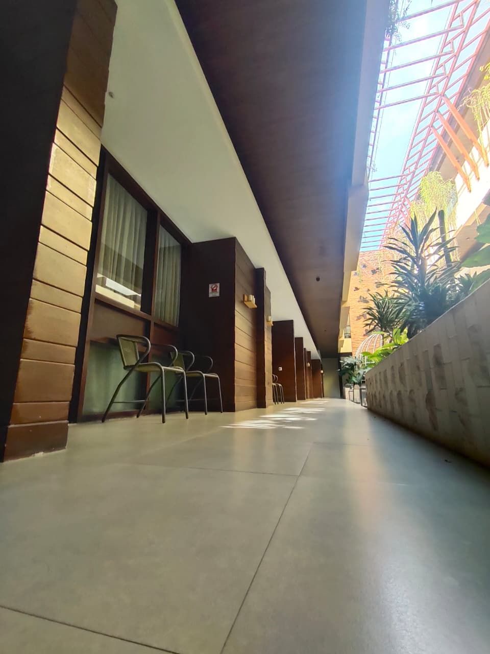 A corridor with a modern design, featuring a glass ceiling and a seating area with chairs.