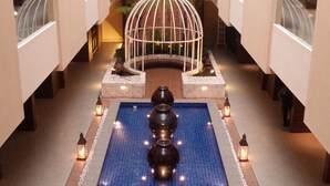 A spacious atrium with a central fountain, surrounded by a tiled floor and decorative lighting. - Sweet Garden Guest House (Malang)
