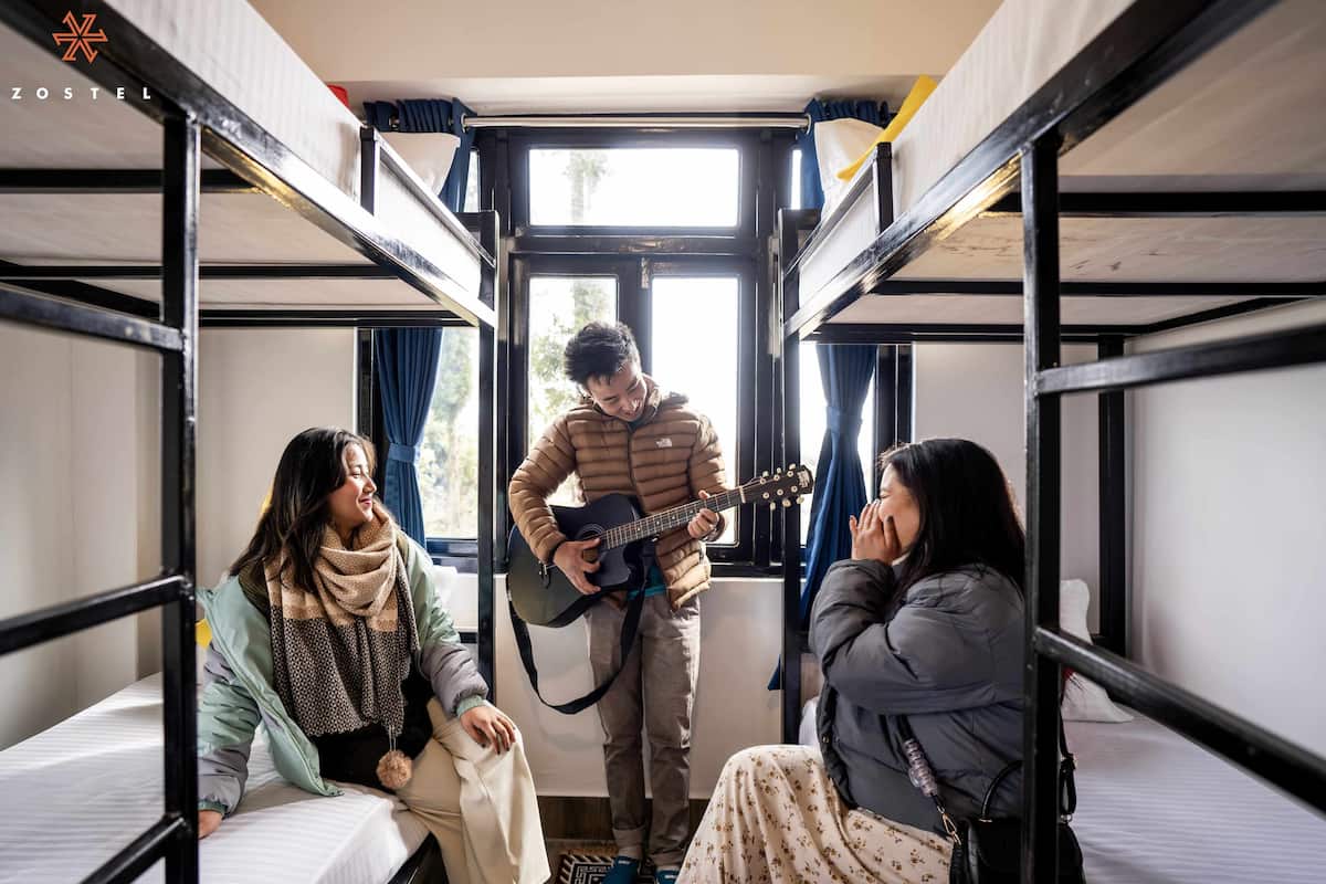 A bunk bed room with a person playing guitar.