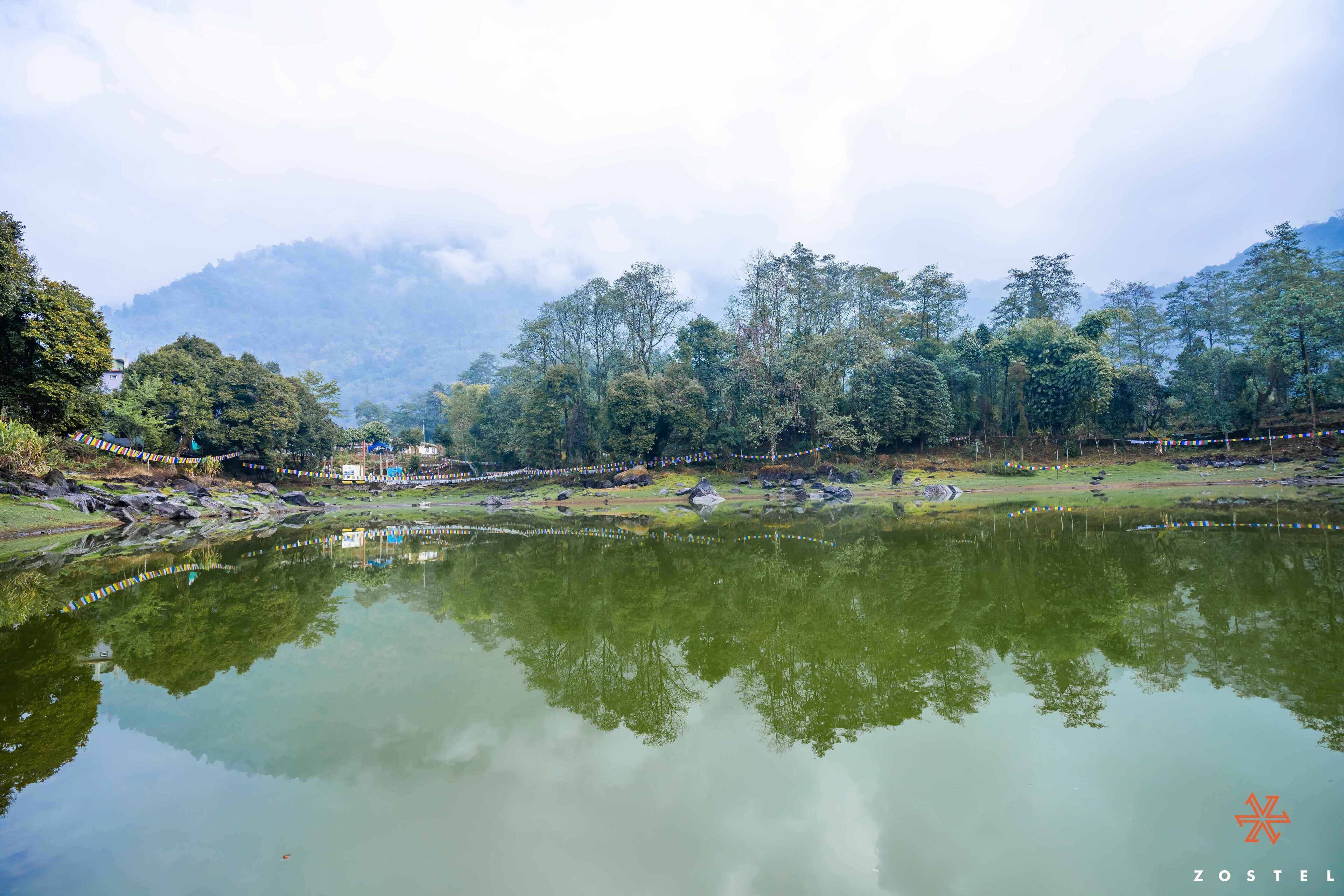A serene lakeside setting with a clear view of the surrounding forest and mountains.